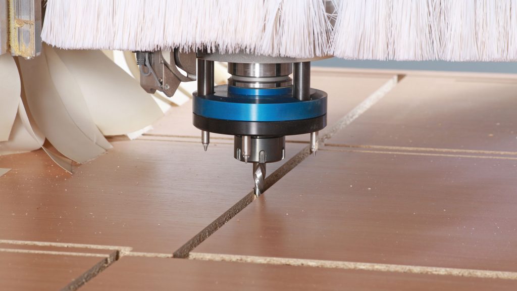 Close-up of a CNC router cutting clean lines through decorative furniture panels — HOMAG application example